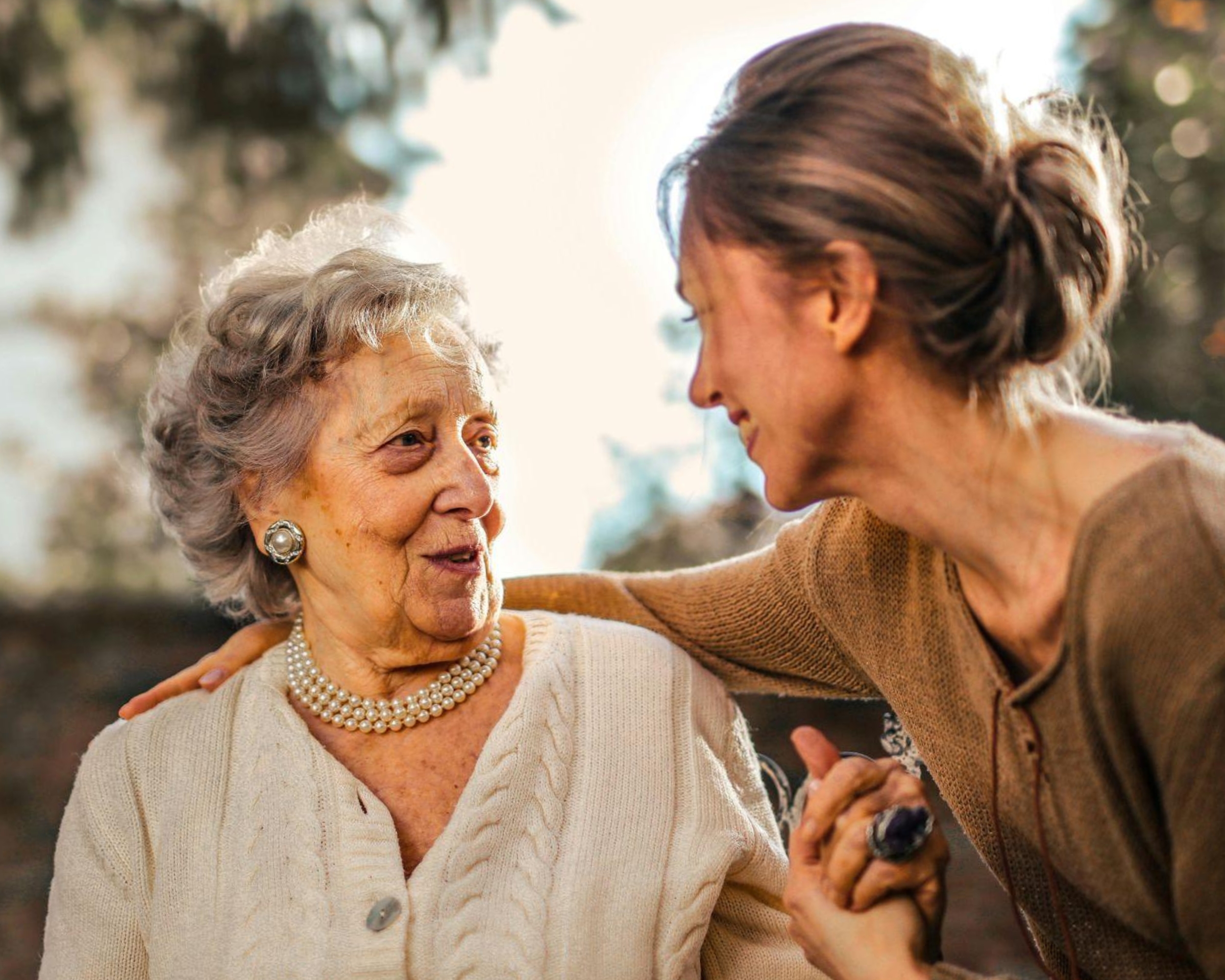 Caregiver holding hand of elderly woman.